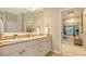 Dual sink bathroom with vanity, framed mirror, and an open doorway to the main bedroom at 8504 Woodbriar Dr, Sarasota, FL 34238