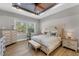 Cozy primary bedroom with wood floors, tray ceiling, and a view of the outdoors at 909 143Rd Ne St, Bradenton, FL 34212