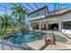 A screened-in outdoor oasis features a custom pool with waterfall, tropical foliage, and covered patio seating at 1110 79Th E St, Palmetto, FL 34221