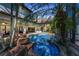 An eye-level shot displays a backyard pool with a rock waterfall, tropical foliage, and a screened enclosure at 1110 79Th E St, Palmetto, FL 34221
