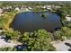 Aerial view showcases a tranquil lake surrounded by lush trees and a charming residential area at 1118 Deardon Dr, Venice, FL 34292