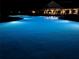 Serene community pool illuminated at night, reflecting a calming blue hue at 15916 Sugar Hill Dr, Punta Gorda, FL 33982