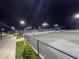 Night view of a well-lit tennis court showcasing meticulously maintained playing surface at 15916 Sugar Hill Dr, Punta Gorda, FL 33982