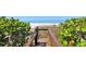 Picturesque beach access boardwalk framed by lush greenery, leading to a tranquil white sand beach and calm blue ocean at 2675 Gulf Of Mexico Dr # 403, Longboat Key, FL 34228