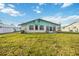 Exterior view of home featuring a large, grassy backyard, and back entry door at 270 E Langsner St, Englewood, FL 34223