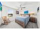 Relaxing bedroom with a wooden bed frame, rocking chair, ceiling fan, and a sun-filled window at 3027 Great Abaco Way, Bradenton, FL 34208