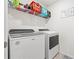 Functional laundry area with a front load washer and dryer, overhead storage and tile flooring at 3027 Great Abaco Way, Bradenton, FL 34208