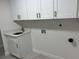 Well-lit laundry room with white cabinets and sink, including washer and dryer hookups at 3320 Riviera Dr, Sarasota, FL 34232