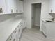 Bright laundry room featuring white cabinetry, quartz countertops, and gold hardware at 3320 Riviera Dr, Sarasota, FL 34232