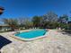 Community pool surrounded by mature trees and brick paved deck at 3333 Ramblewood Pl, Sarasota, FL 34237