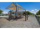 Community playground structure with sun shade, monkey bars, slide, and climbing features over wood chip ground cover at 415 63Rd St, Holmes Beach, FL 34217