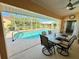 Covered patio with a dining set overlooking a screened in-ground swimming pool with a view of the backyard at 417 Firethorn Ave, Englewood, FL 34223