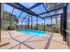 Enclosed pool featuring clear blue water within a screened lanai overlooking tropical landscaping at 4704 Coral Lake Dr, Bradenton, FL 34210