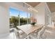 Dining room features a large wood table, modern chandelier, and views of lush tropical landscaping at 600 De Narvaez Dr, Longboat Key, FL 34228