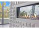 Close-up of a modern fireplace with glass stones, a textured white surround, and a view of the patio at 600 De Narvaez Dr, Longboat Key, FL 34228