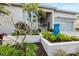 Landscaped front yard featuring a blue water feature, lush plants, and palm trees, adding curb appeal at 600 De Narvaez Dr, Longboat Key, FL 34228