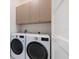 Modern laundry room featuring front load washer and dryer with upper cabinets for storage at 600 De Narvaez Dr, Longboat Key, FL 34228