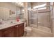 Tiled bathroom featuring a vanity, toilet, and shower-tub combination with glass doors at 6605 Waters Edge Way, Lakewood Ranch, FL 34202