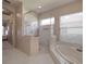 Bright bathroom with a glass-enclosed shower, a soaking tub, and white tiled floors at 6605 Waters Edge Way, Lakewood Ranch, FL 34202