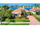 Waterfront home features a tile roof, manicured lawn, lush landscaping, and a brick driveway at 6605 Waters Edge Way, Lakewood Ranch, FL 34202