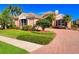 Home exterior featuring a tile roof, lush landscaping, manicured lawn, and brick driveway at 6605 Waters Edge Way, Lakewood Ranch, FL 34202