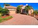 Front exterior showcasing brick driveway, lush lawn and mature landscaping at 6605 Waters Edge Way, Lakewood Ranch, FL 34202