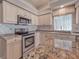 A well-lit kitchen with granite countertops and stainless steel appliances offers a sleek and modern culinary space at 6605 Waters Edge Way, Lakewood Ranch, FL 34202