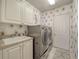 Laundry room with floral wallpaper, a utility sink, and modern, front-loading appliances at 6605 Waters Edge Way, Lakewood Ranch, FL 34202