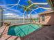 A screened-in pool with a brick patio overlooking a serene lake and clear blue skies in this backyard oasis at 6605 Waters Edge Way, Lakewood Ranch, FL 34202