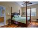 Bedroom with a four-poster bed, hardwood floors, and a tray ceiling with fan at 6619 Copper Ridge Trl, Bradenton, FL 34201