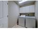 Functional laundry room with a washer, dryer, white cabinets, and tiled floor for easy maintenance at 6619 Copper Ridge Trl, Bradenton, FL 34201