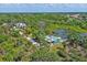 Wide aerial view of a waterfront property with mature trees, gravel driveway, and views of the surrounding neighborhood at 6737 Lincoln Rd, Bradenton, FL 34203