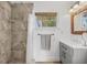 Bathroom featuring a stone tiled shower, grey vanity, and a natural light filled window at 6737 Lincoln Rd, Bradenton, FL 34203