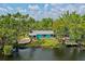 Charming waterfront home featuring a vibrant blue exterior, dock, and a serene view of the water at 6737 Lincoln Rd, Bradenton, FL 34203