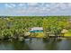 Waterfront property showcases a serene location with a vibrant blue home, surrounded by lush greenery and tranquil water views at 6737 Lincoln Rd, Bradenton, FL 34203