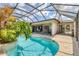 Gorgeous pool with brick pavers, lush landscaping, screen enclosure, seating, and access to the home's interior at 6820 19Th W Ave, Bradenton, FL 34209