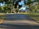 Long driveway leads to a quaint yellow home surrounded by lush greenery and mature trees at 7036 Clark Rd, Sarasota, FL 34241