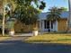 Charming yellow home featuring a metal roof, tropical landscaping, and a welcoming front entrance at 7036 Clark Rd, Sarasota, FL 34241