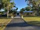 Yellow home with a metal roof, lush landscaping, and a paved walkway leading to the front door at 7036 Clark Rd, Sarasota, FL 34241