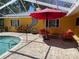 An outdoor pool area with a red umbrella and outdoor furniture for relaxation at 7036 Clark Rd, Sarasota, FL 34241