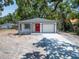 Single-story home with a bright red front door and an attached garage under a canopy of trees at 732 15Th E St, Bradenton, FL 34208