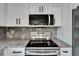 Stainless steel stove and overhead microwave with gray countertops and modern backsplash at 732 15Th E St, Bradenton, FL 34208