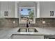 Close up of the stainless steel kitchen sink with view of the front yard out the window at 732 15Th E St, Bradenton, FL 34208