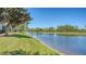 Scenic pond view near a golf course framed by mature trees, with a manicured green lawn at 7687 Sweetbay Cir # 7687, Bradenton, FL 34203