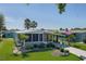 Single-story home with manicured lawn, palm trees, an American flag, and a covered carport at 8402 Princess Ct, Palmetto, FL 34221