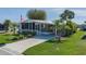 Charming single-story home with manicured lawn, palm trees, a covered driveway, and an American flag at 8402 Princess Ct, Palmetto, FL 34221