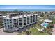 A view of white multi-story condos with a pool, trees, parking, and access to ocean views at 8735 Midnight Pass Rd # 306B, Sarasota, FL 34242