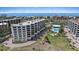 An aerial view of white multi-story condominiums with ocean views, a pool, and manicured landscaping at 8735 Midnight Pass Rd # 306B, Sarasota, FL 34242