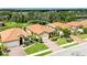 Wide shot of the home featuring a red tile roof, beautiful landscaping, and a brick paver driveway at 10015 Marbella Dr, Bradenton, FL 34211