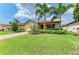 Charming home with lush green lawn, mature palm trees, and a brick driveway at 10015 Marbella Dr, Bradenton, FL 34211